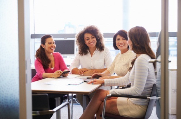 Four professional women discuss Selective's Women at Work Group at a conference table.